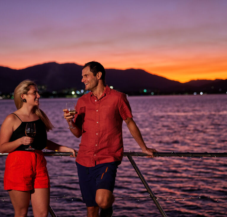 Couple having a drink on the deck of Spirit of Cairns at dusk